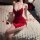 A woman poses on a bed adorned with rose petals, wearing a luxurious red sensual lingerie set featuring a backless slip dress...