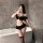 Woman in black sexy lingerie set with crop top and pleated mini skirt, posing by bathtub — seductive uniform style outfit.
