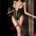 Woman wearing black lace sleepwear set with garter straps and fishnet stockings, holding wine glass.