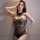 Woman wearing black sheer lace bodysuit with cutout details, posing confidently against neutral wall – nightsiyese sexy trans...