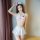 Woman modeling white nurse costume lingerie set with red cross details, featuring halter top and pleated mini skirt for adult...