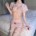 Woman wearing pink nurse costume lingerie set with side-tie straps, sheer bra, mini skirt, and matching hat on bed.