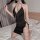 Woman wearing black ol secretary sexy lingerie dress with open-crotch, thigh slit, and adjustable straps on bed.