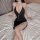 Woman wearing black ol secretary sexy lingerie dress with deep v-neck, thigh slit, and adjustable straps on bed.