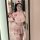 A woman poses in a mirror wearing an oushilin sweet nurse costume set, featuring a pink cropped top with buttons and a matchi...
