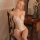 Blonde woman in white passion lace bodysuit, sheer mesh sleepwear with floral details, seated elegantly on wooden chair.