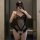 A woman poses in a mirror wearing a black bodysuit adorned with lace and sheer fabric, featuring butterfly embellishments and...