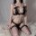 Woman wearing pearl temptation thong lingerie set with lace bra, pearl detail, and fishnet stockings on white fur rug.