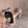 Woman in pink leopard print bodysuit with furry ears and tail, posing on fluffy rug for cute role play look.