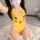 A woman wearing a yellow pikachu-themed bodysuit with red cheeks, sitting on a white rug indoors. the outfit features playful...
