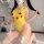 A woman wearing a yellow pikachu-themed bodysuit with white stockings featuring bows, posing indoors with balloons and flower...