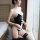 Woman modeling black bunny girl lingerie set with white lace-up front, open-crotch design, and matching garter stockings.