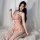 A woman poses elegantly in a peach-colored bodysuit adorned with floral patterns, featuring a deep v neckline and lace detail...