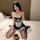 Woman wearing a black and white lace lingerie set with thigh-high stockings, sitting on a bed holding a coffee cup.