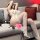 Woman lounging on sofa in white sheer lace bodysuit with open-crotch design, fishnet stockings, and snake-print heels.
