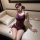 Woman in purple lace lingerie set with matching blindfold, sitting on a beige couch.
