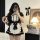 A woman poses with a smartphone, wearing a black and white maid costume featuring ruffles and bows. the outfit includes a dre...