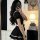 A woman poses in a black maid costume with white accents, featuring puffed sleeves and a ruffled skirt, perfect for cosplay o...