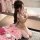 Woman in beige lace bondage outfit with sheer gloves, kneeling beside pink roses—sensual date night or bedroom wear.