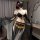 Woman wearing black plus size sensual lingerie set with gold coin belt, sheer sleeves, and fringe bra for elegant bedroom int...