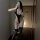 Woman in mirror wearing black plus size sexy bodysuit set with open-crotch design, sheer stockings, and lace garters.