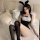 A woman poses on a bed wearing a black bunny costume with white accents, featuring thigh-high stockings. the outfit includes ...