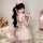 Woman modeling pink lace bunny girl costume with ruffled trim and sheer mesh details, perfect for cosplay or themed events.
