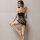 Woman wearing black plus size sexy lace fishnet bodystocking with open-crotch design, posing against wall.