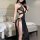 Woman wearing a black sheer lingerie set with gold chains, featuring a halter top and long robe with high slit.
