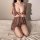 Woman kneeling on bed in sheer lace lingerie set, deep v-neck with ruffle straps, sensual nightwear for women.