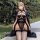 Woman in black plus size sexy lingerie set with heart-shaped bra and sheer thong, posing outdoors.