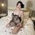 Woman in plus size sheer black lingerie set with mesh cami and shorts, sitting on bed with rose petals.