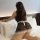 Woman wearing black lace lingerie set with white bow, sheer sleepwear on bed.