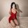 Woman wearing red plus size sexy lingerie set with lace details, kneeling on bed for elegant sleepwear look.