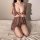 Woman in elegant lace lingerie set, kneeling on bed, showcasing plus size sexy sleepwear outfit.