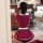 A woman wearing a red maid costume with a white apron, captured from behind as she takes a photo in a room setting.