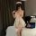 Woman in pink checkered maid costume with lace petticoat, backless design, and matching hat, posing in bedroom.
