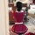 A woman wearing a red maid costume with white apron, captured from behind as she takes a photo in a room setting.