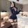 Woman in bedroom wearing blue police-themed bodysuit with garter straps, holding phone and toy gun—plus size sexy role play c...