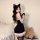 Woman modeling a black plus size sexy sleepwear set with cat ears, featuring a plush bodycon wrap skirt and matching top.