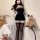 Woman modeling black plush bodycon wrap skirt and matching top with cat ears, paired with thigh-high stockings, in a cozy bed...