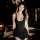 A woman poses elegantly in a black swimsuit featuring a deep v-neckline and flared skirt, exuding allure and sophistication.