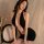 A woman poses elegantly wearing a black halter dress with a plunging neckline, paired with delicate silver jewelry. the outfi...