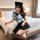 A woman wearing a navy sailor collar outfit with a cute black headband, sitting on a bed. the ensemble features a short skirt...