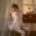 A woman sits elegantly on a chair, wearing a delicate lace bodysuit with sheer fabric details. the design features intricate ...