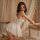A woman poses elegantly in a white lace sleepwear set, featuring a sheer babydoll nightgown with a backless design, perfect f...