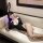 Woman lounging on sofa in black bunny lingerie set with fishnet stockings, holding phone. pure & alluring lingerie set – sedu...