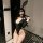 Woman wearing black bunny lingerie set with fishnet stockings and lace mask, holding gloves in mouth.