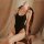 A woman reclines on a chair wearing a black open-crotch ice-silk slip dress, exuding elegance and allure. the luxurious fabri...