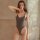 A woman poses in a sleek, dark gray one-piece swimsuit with thin straps and an open crotch design, featuring a smooth fabric ...